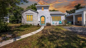 A two-story house with a stone facade, a green door, and yellow-framed windows. - Spanish Beach Bungalow Mainhouse (Holly Hill)