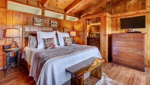 Ein Schlafzimmer einer Holzhütte mit Bett, Schminktisch und Fernseher.