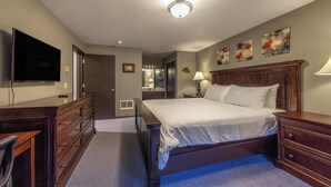 Une chambre d’hôtel dotée d’un grand lit, d’une commode, d’un bureau avec une chaise, d’un téléviseur à écran plat et d’œuvres d’art accrochées aux murs.