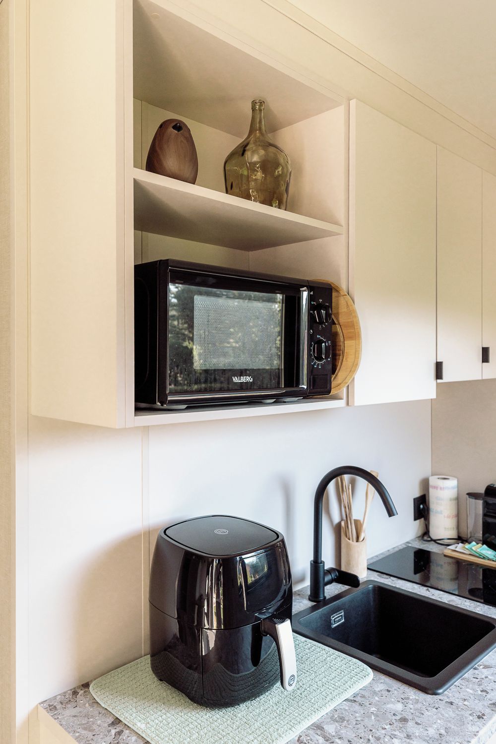 Een keuken met een magnetron, waterkoker en spoelbak.