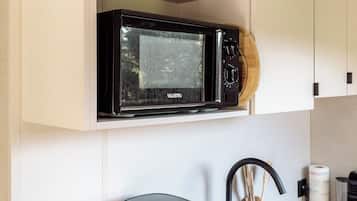 Een keuken met een magnetron, waterkoker en spoelbak.