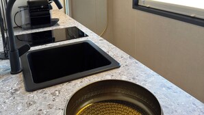 A kitchen with a countertop, a sink, a window, and an air conditioning unit.