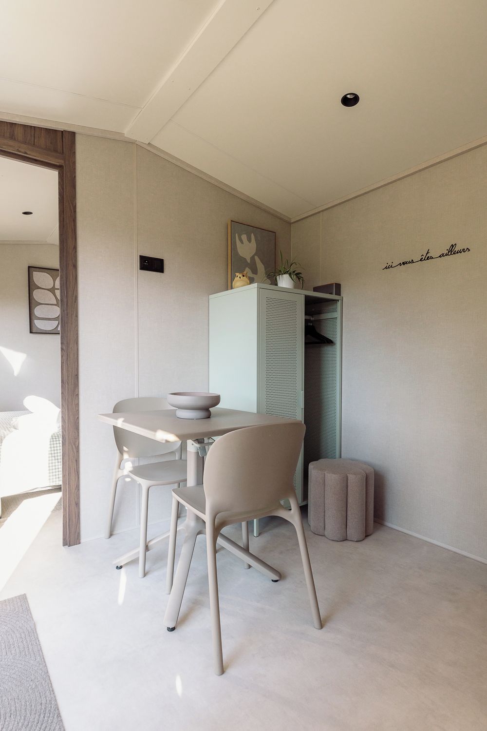Ein schlicht eingerichteter Essbereich mit Tisch, Stühlen und einem Schrank.