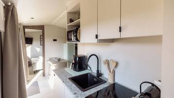 Una cocina moderna con un lavamanos negro, una cafetera y utensilios de madera.