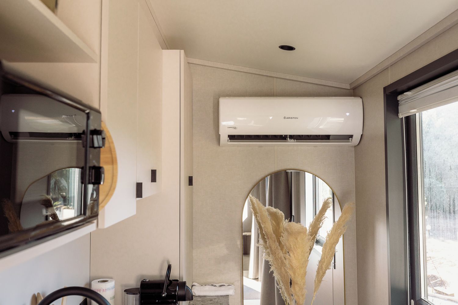 A modern bathroom with a large mirror, a toilet, a sink, and an air conditioning unit mounted on the wall.