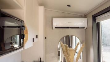 A modern bathroom with a large mirror, a toilet, a sink, and an air conditioning unit mounted on the wall.