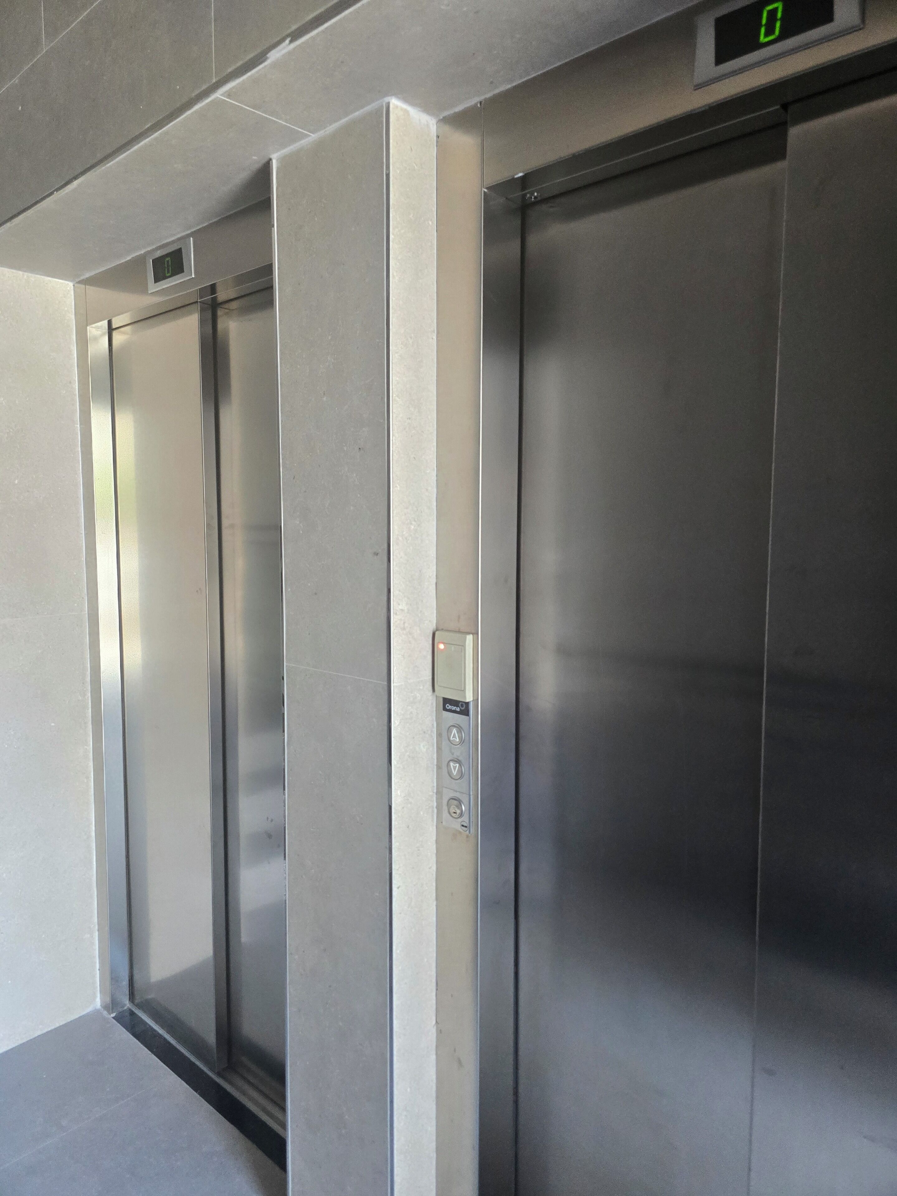 Een moderne lift met een digitaal scherm, bedieningspaneel en een metalen afwerking.