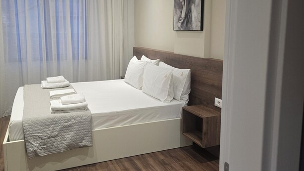 Ein modernes Hotelzimmer mit einem großen Bett, einem Nachttisch und einem Bild an der Wand.