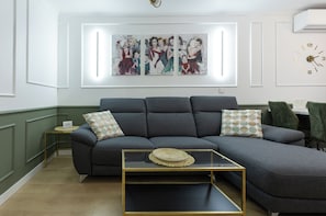 A modern living room with a grey sectional sofa, a glass coffee table, and a wall-mounted clock.