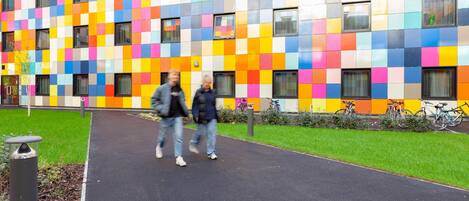 A building with a colorful mosaic facade and a paved walkway.