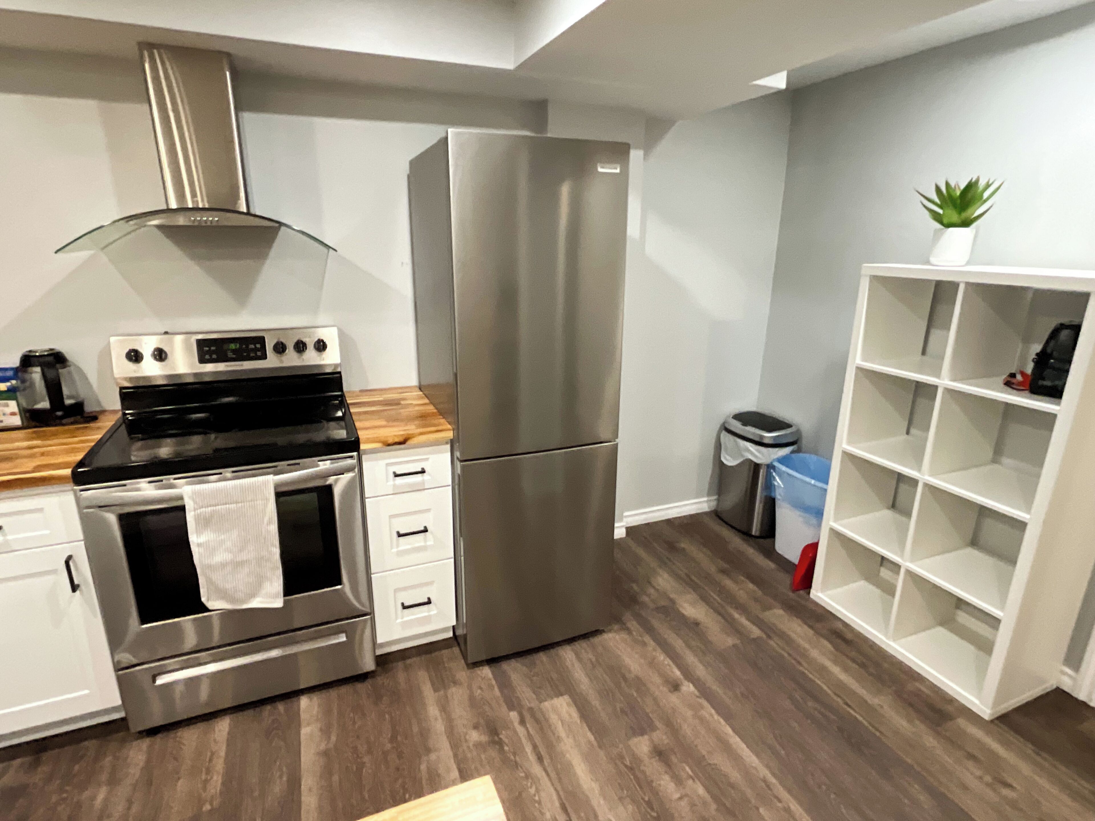 Une cuisine moderne dotée d’appareils électroménagers en acier inoxydable, de plans de travail en bois et d’une bibliothèque intégrée.