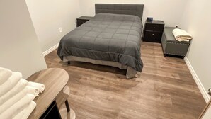 A bedroom with a bed, bedside tables, a bench, and a small bedside table with a clock.