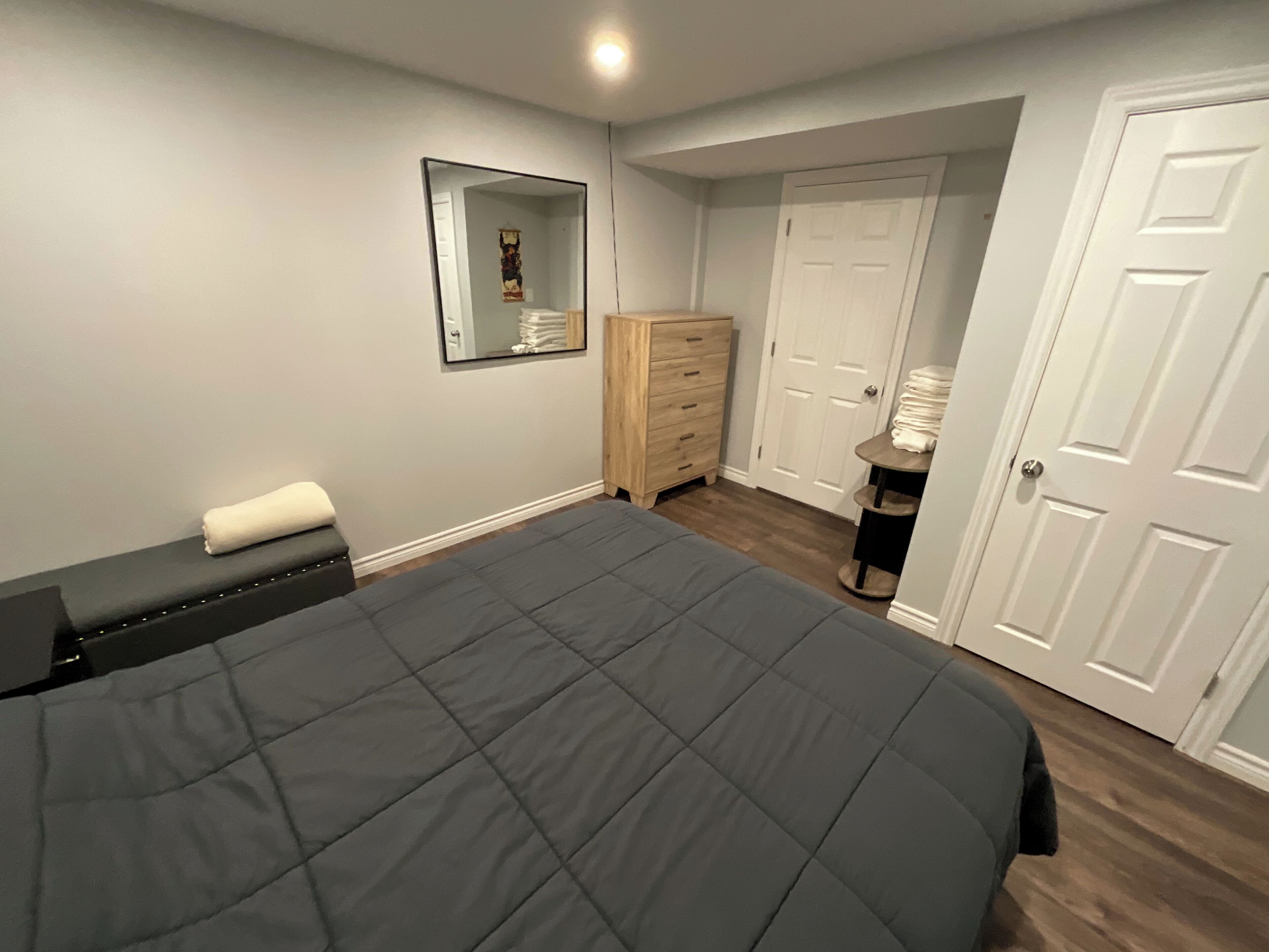 A bedroom with a large bed, a dresser, a mirror, and a door.