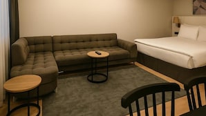 A modern hotel room with a sectional sofa, a single bed, a small round table, and a chair. - Sare Apartment Sultanahmet (Istanbul)
