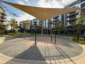 A circular outdoor area with exercise equipment, surrounded by a paved walkway and a large canopy. - Stylish 2BR Serviced Apart at Cairo Festival City (Cairo Governorate)