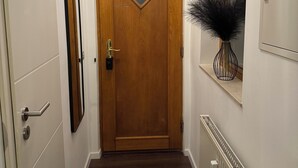 Ein Flur mit einer Holztür, einem Heizkörper und einem Spiegel an der Wand.