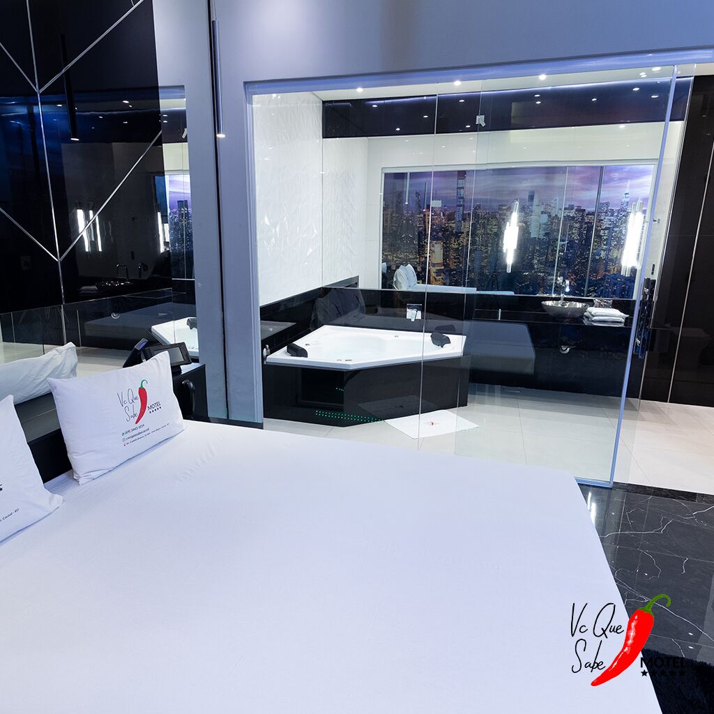 Una habitación de hotel moderna con vistas a la ciudad, una cama grande, una zona de estar y un baño separado con bañera.