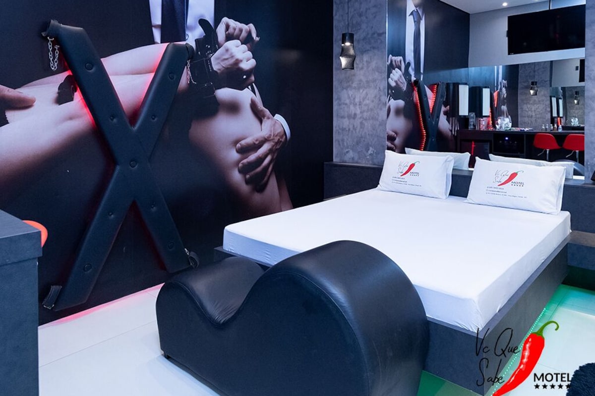 Una habitación de hotel moderna con una cama grande, un sillón negro y una pared decorada con un cartel de gran tamaño.