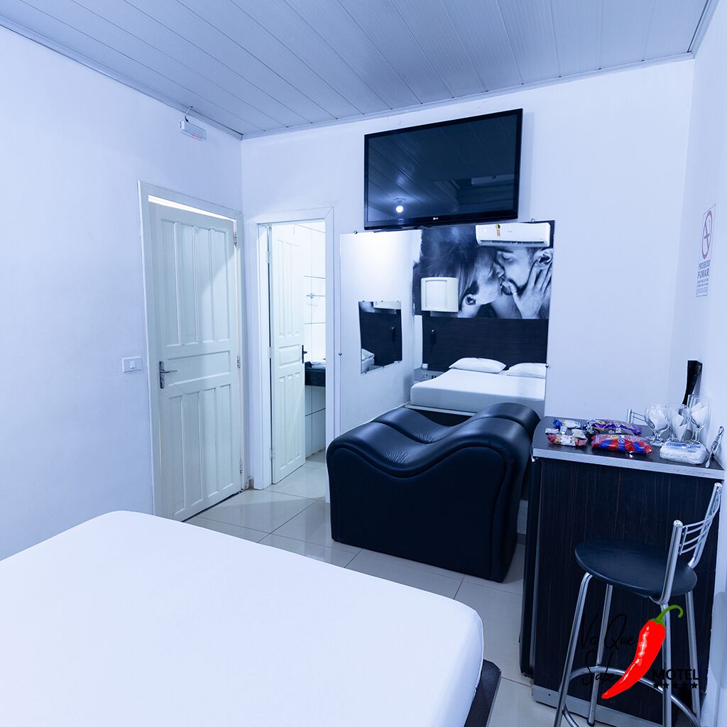 A modern hotel room with a bed, a desk, a TV, and a bathroom visible through an open door.