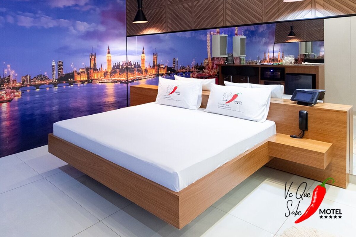 Una habitación de hotel moderna con una cama grande, un mural de paisaje urbano, paneles de madera y una minibar.