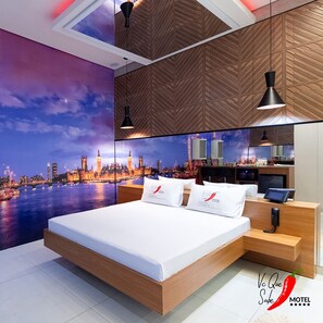 Una habitación de hotel moderna con una cama grande, un mural de paisaje urbano, paneles de madera y una minibar.