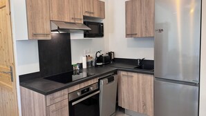 Een moderne keuken met houten kastjes, een roestvrijstalen koelkast, een inbouwoven en een magnetron.