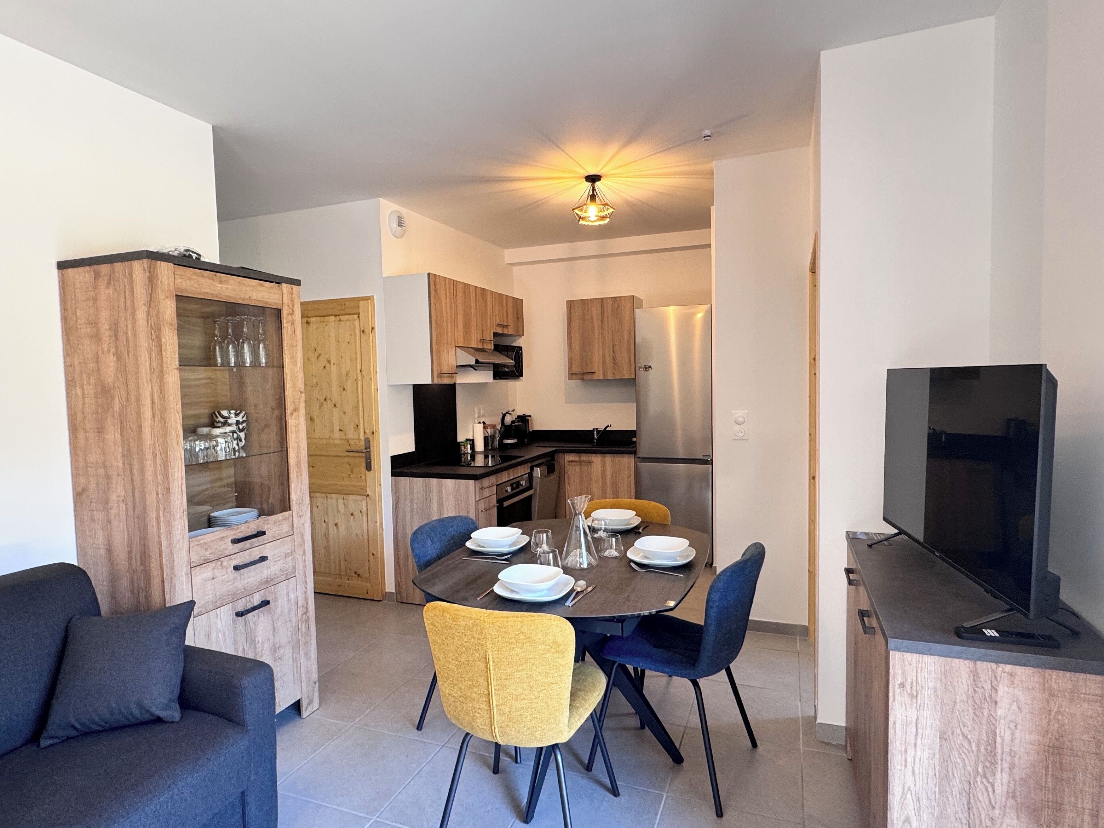 A modern kitchen with wooden cabinets, a built-in oven, and a stainless steel refrigerator.
