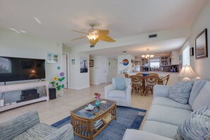 A spacious living room with a television, seating area, dining table, and kitchen in the background. - Salt Life – 2Bed/2Bath Beachfront Condo with Pool & Elevator Access (Marathon)