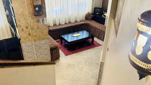 Un salon avec un canapé marron, une table basse et un tapis à motifs.