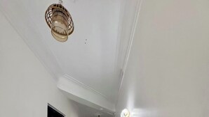 Un couloir aux murs blancs, doté d’un sol en marbre et d’un luminaire suspendu.