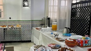 Un buffet proposant une variété de plats et de boissons, notamment un distributeur de punch aux fruits et une machine à café.