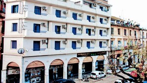 Un immeuble à plusieurs étages, avec un commerce au rez-de-chaussée et plusieurs balcons.