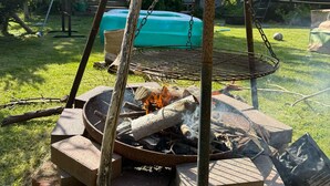 Un giardino sul retro con un braciere, altalene e una casa sullo sfondo.