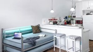 Un ambiente compatto con divano, angolo cottura e ventilatore a soffitto.