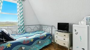 Una camera da letto con un letto, una televisione, una cassettiera e una finestra con tende.