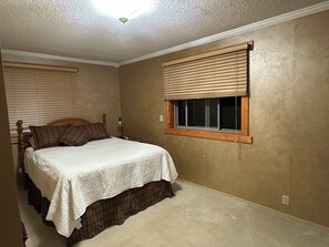 A bedroom with a bed, a window with blinds, and a ceiling fan.
