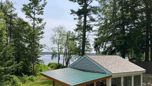 Una piccola cabina con un portico coperto, un patio e vista su un lago circondato da alberi.