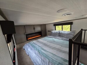 A bedroom with a bed, a fireplace, and a window.