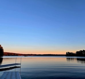 Un lac paisible, avec une jetée en bois qui s’avance sur l’eau.