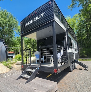 A mobile home with a covered porch area, a ramp for access, and a small deck.