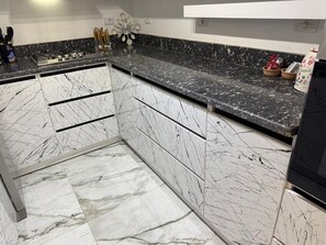 Eine Küche mit weißen Marmor Schränken und einer Arbeitsplatte aus schwarzem Granit.