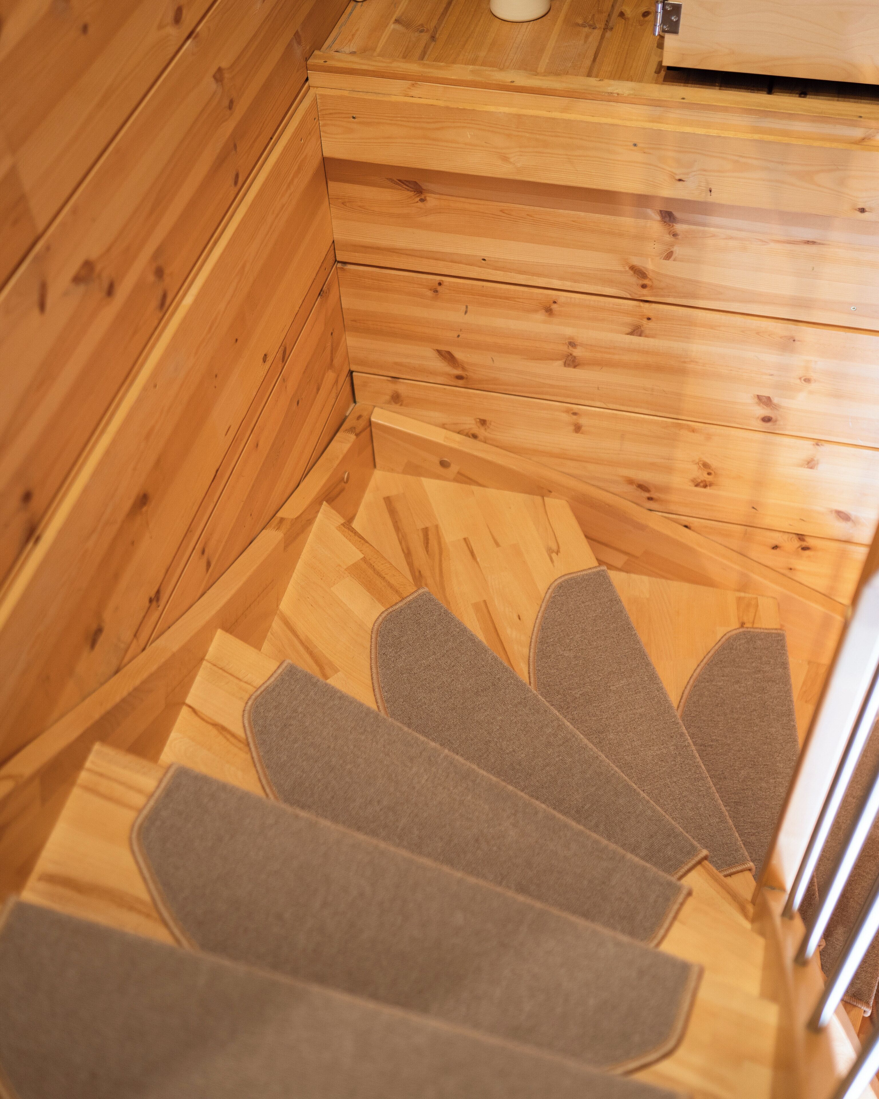 A wooden staircase with a handrail and carpeted steps.