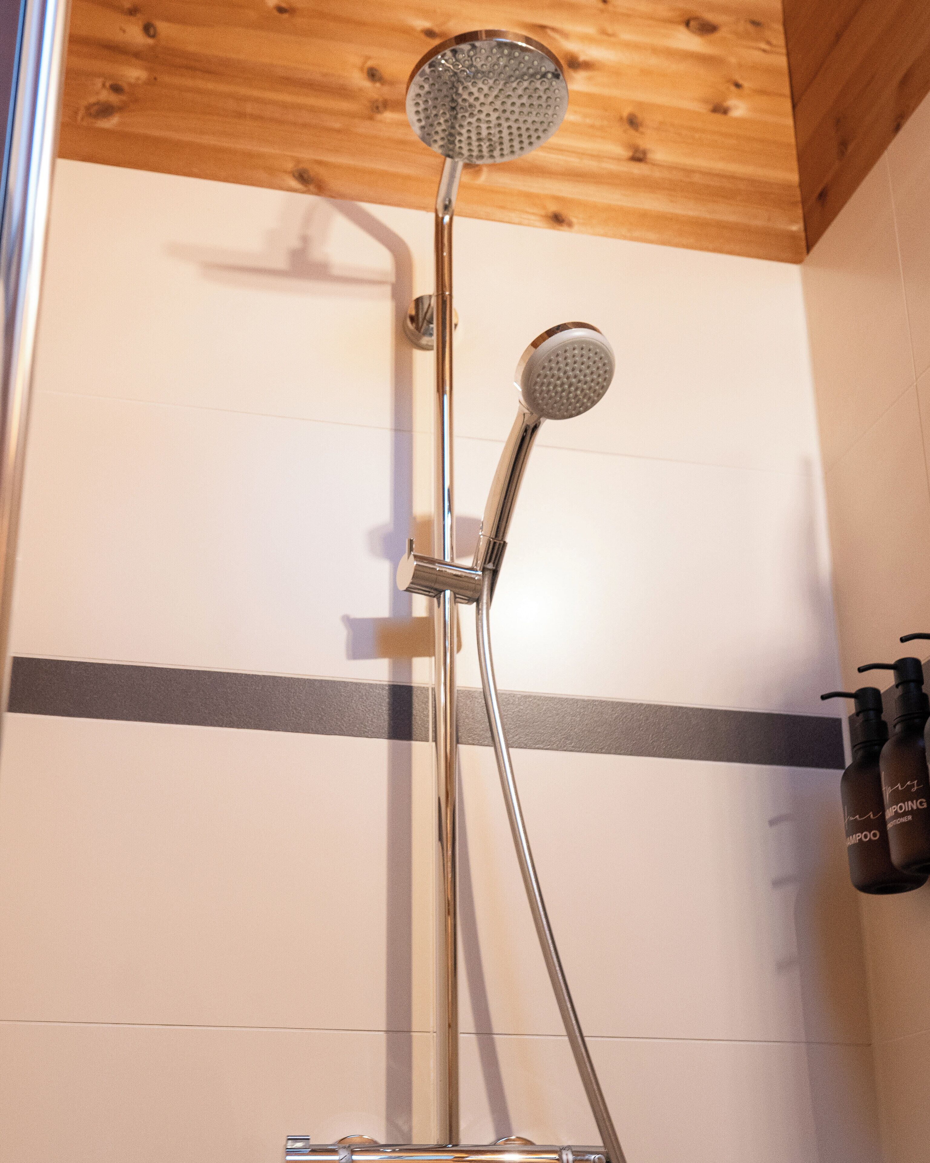 Une douche équipée d’un pommeau de douche à main et d’un pommeau de douche fixe fixé au mur.