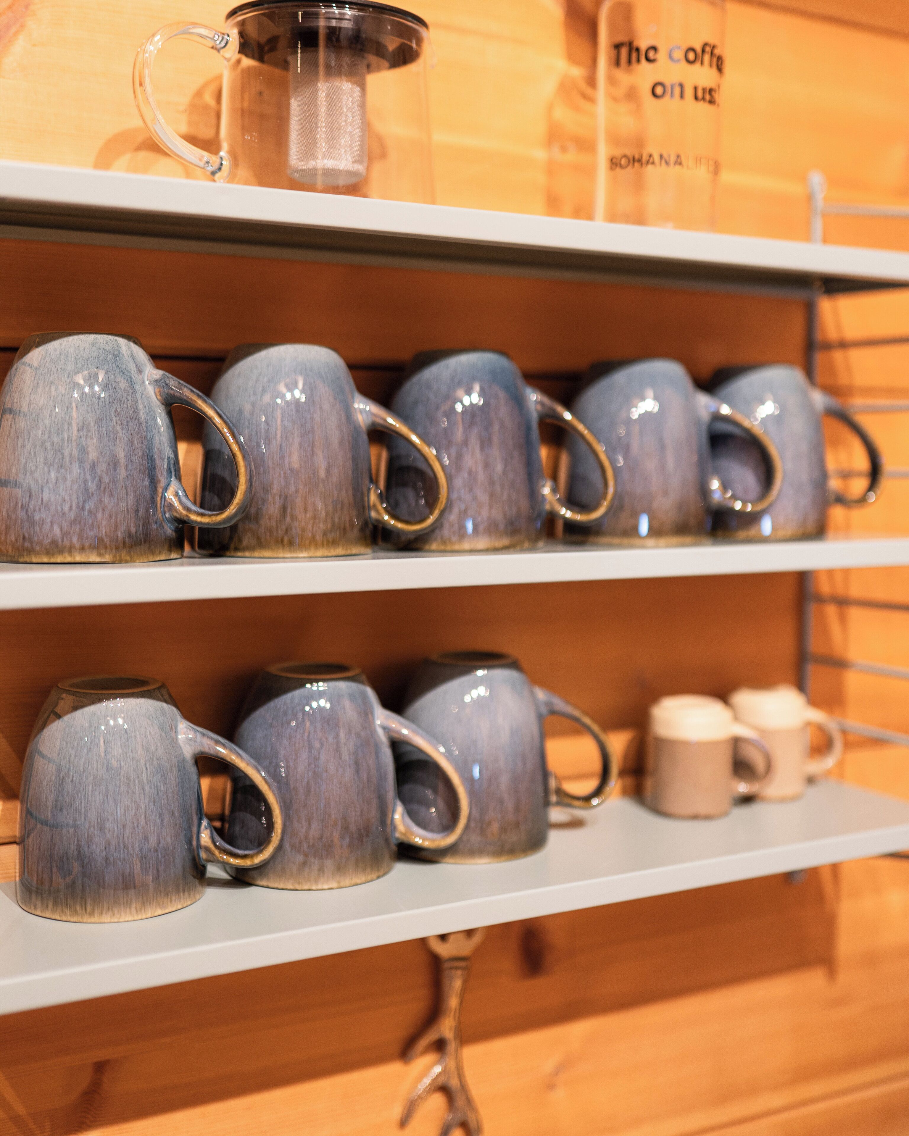Een plank met keramische mokken en een theepot.
