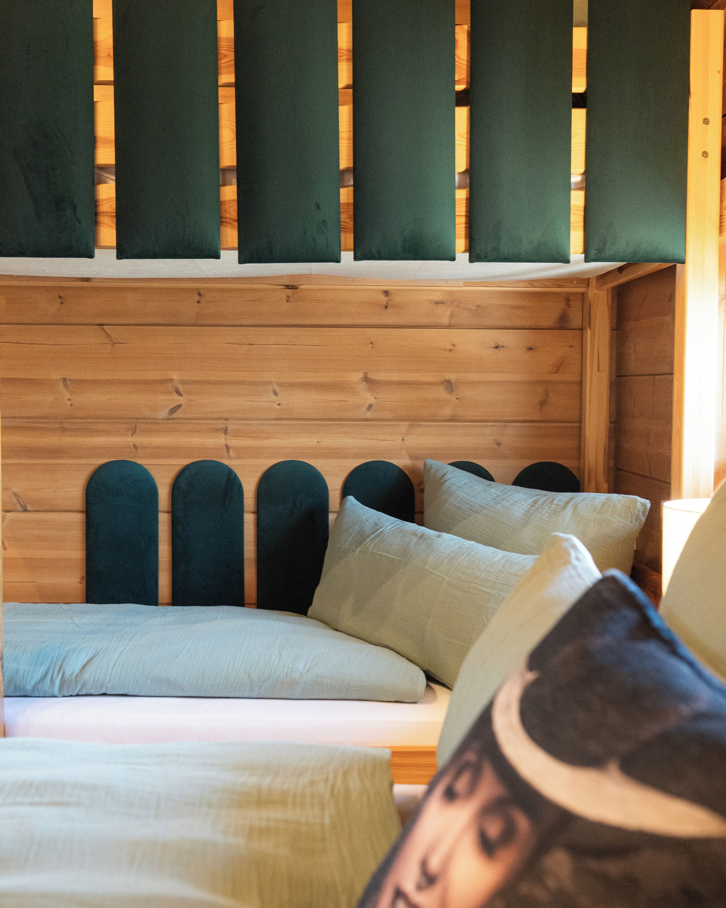 Une tête de lit en bois agrémentée de plusieurs coussins et d’un oreiller au motif graphique.