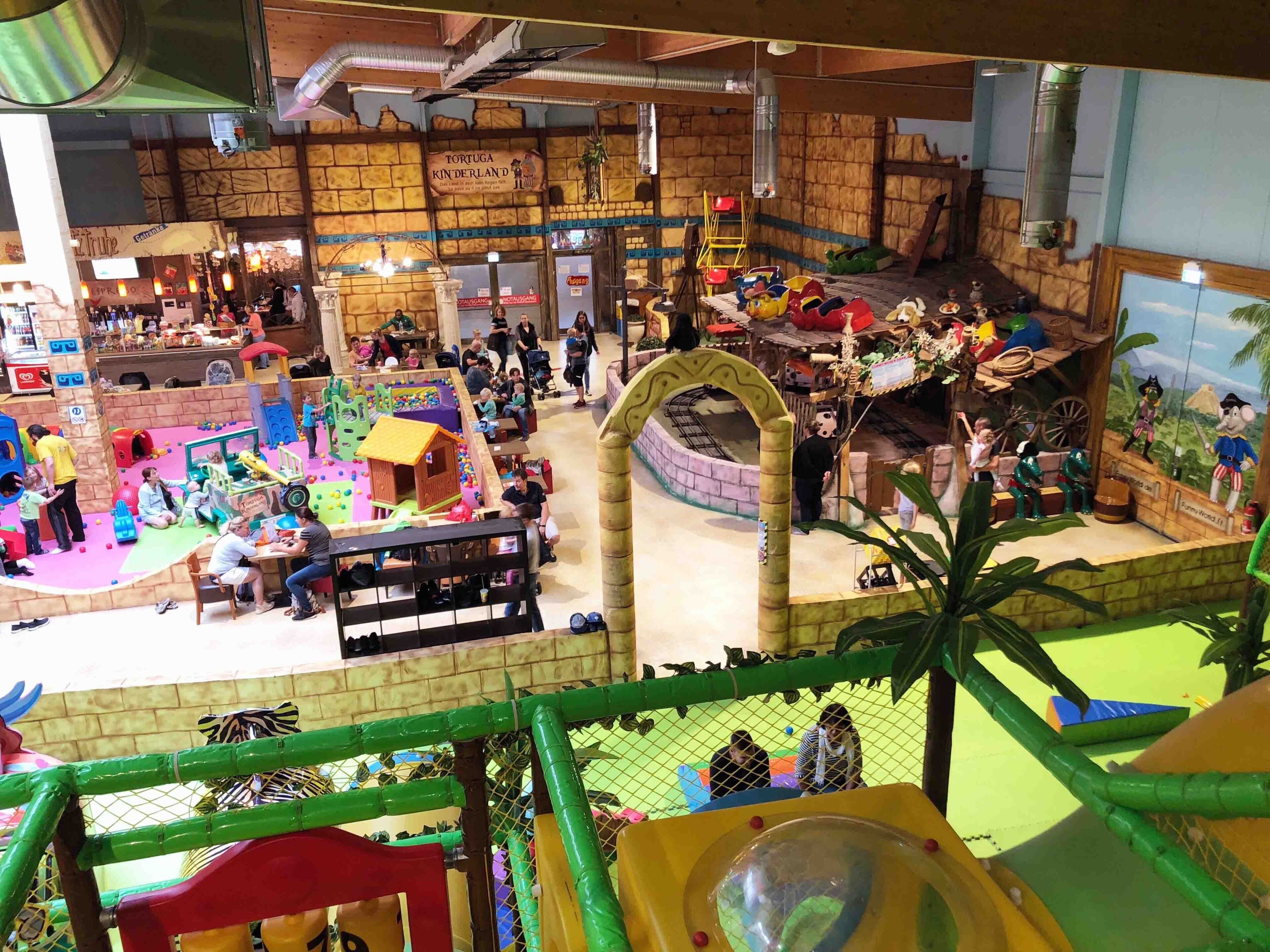 An indoor play area with various play structures and a climbing wall.