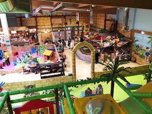 Zona de juegos interior con diversas estructuras y una pared de escalada.