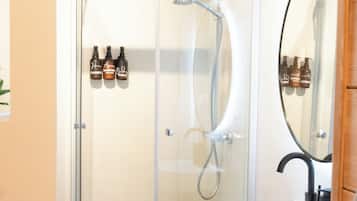 A modern bathroom with a glass shower enclosure, a white sink, and a wooden vanity.