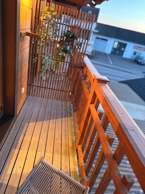 Un muelle de madera con un banco y barandilla, con vista a una calle.
