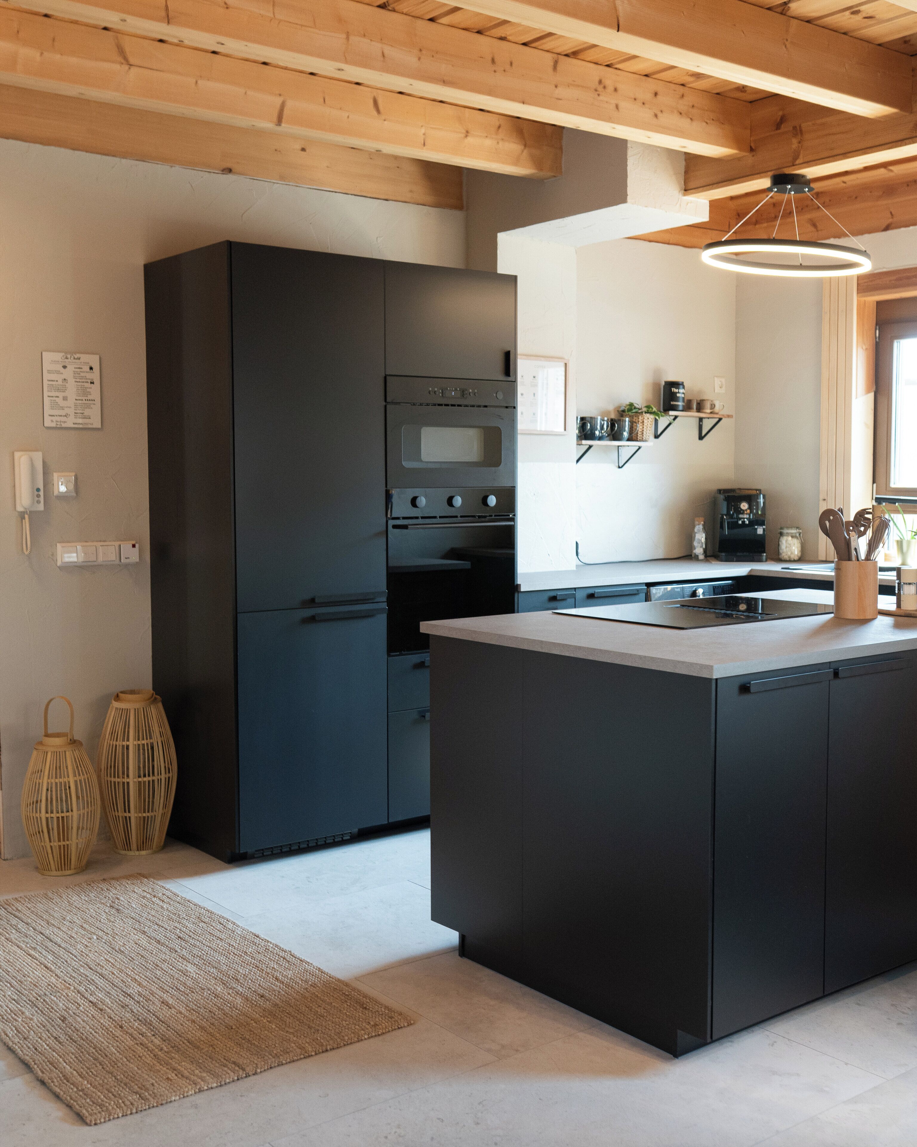 A modern kitchen with a central island, built-in appliances, and a wooden ceiling.